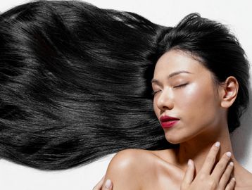 Woman with long, flowing black hair and closed eyes.