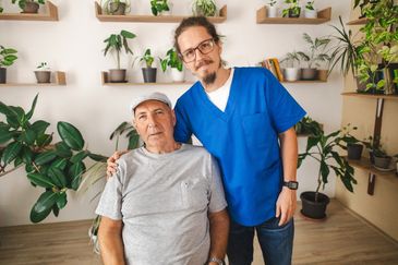 Older man and healthcare professional posing together.