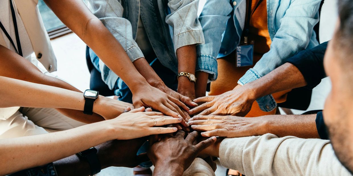 Diverse group joining hands in unity and teamwork.