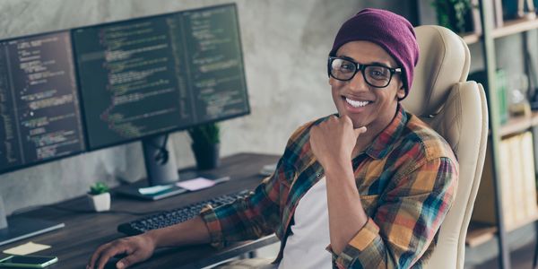 Smiling engineer working at a desk with a code monitor. In this represents our engineers work tirele