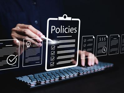 Person interacting with digital policy documents using a stylus and keyboard.