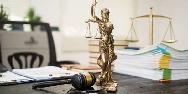 Legal office desk with Lady Justice statue, gavel, and documents.