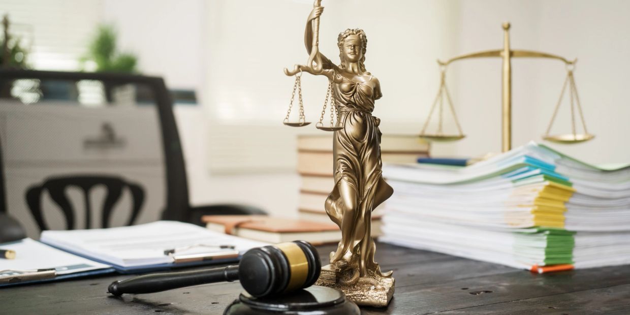 Judge's gavel and Lady Justice statue on a desk.