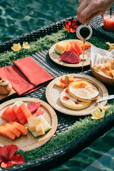 Breakfast served on a floating tray by the pool with pancakes and fresh fruit.
