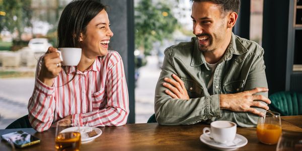 A joyful couple laughing and enjoying coffee together at a café — a cozy moment from our catering menu, perfect for event catering and office catering.