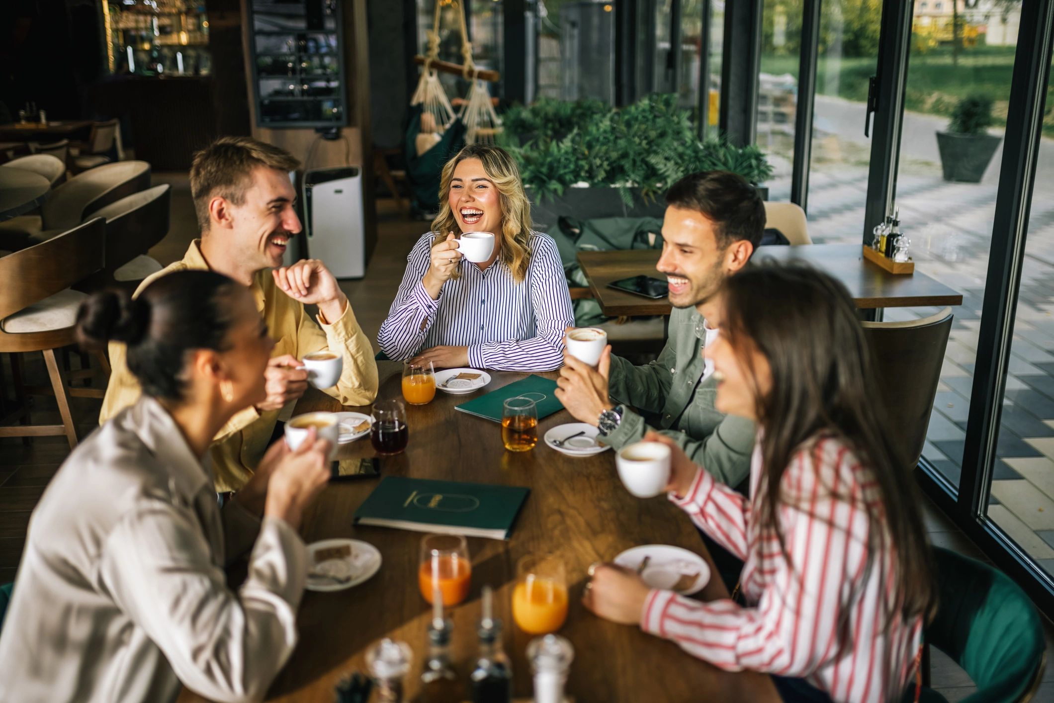 Group of friends enjoying coffee and laughter at a cafe.