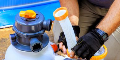 Person assembling a pool pump with gloves and tools.