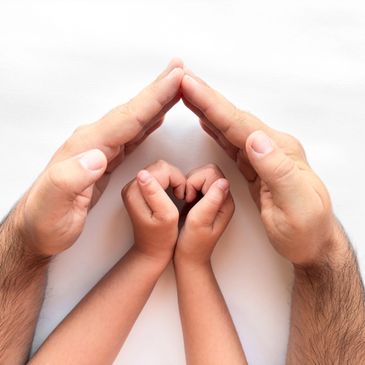 Adult hands forming a protective roof over child hands symbolizing care.