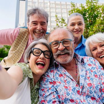 Group of happy older adults taking a selfie outdoors.
