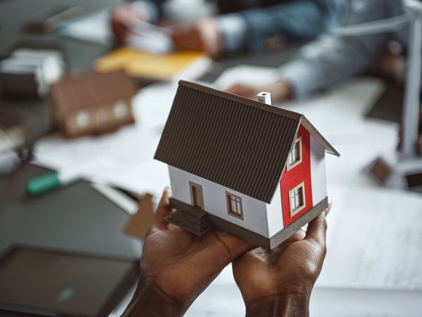 Hands holding a detailed miniature house model in a professional setting.