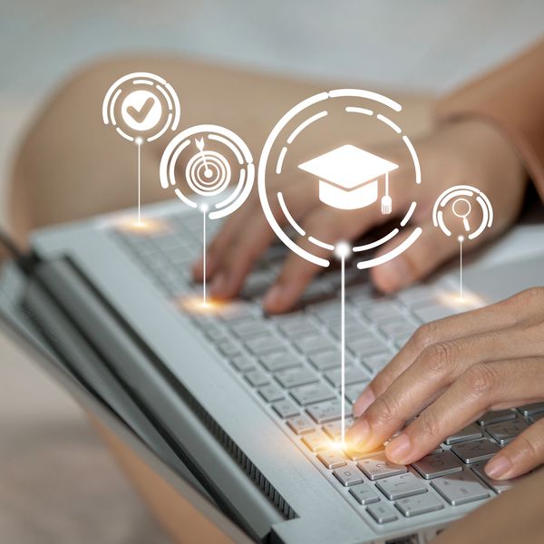 Hands typing on laptop with education and success icons overlay.