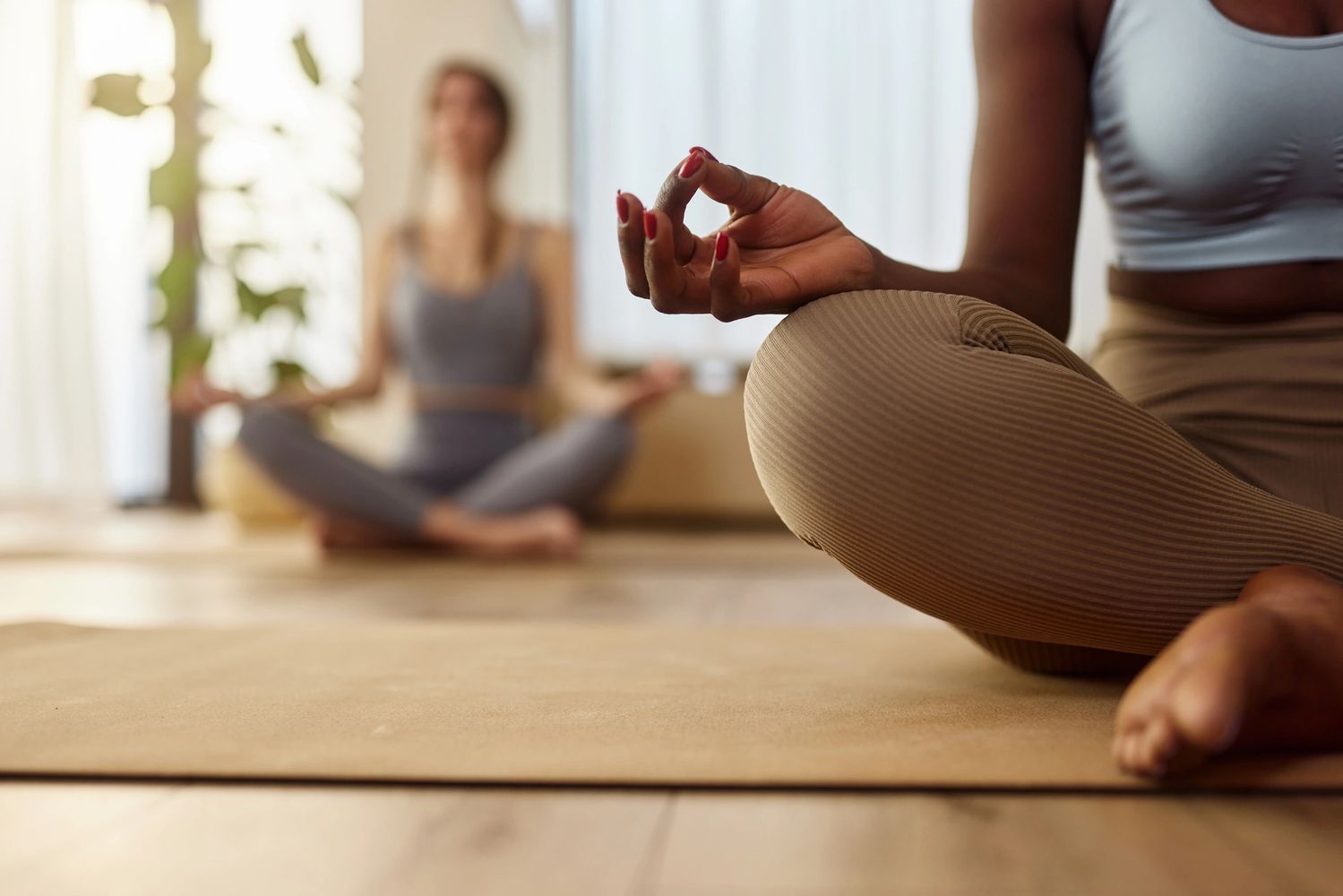 Two women meditate in a peaceful yoga studio, focusing on mindfulness and calm.