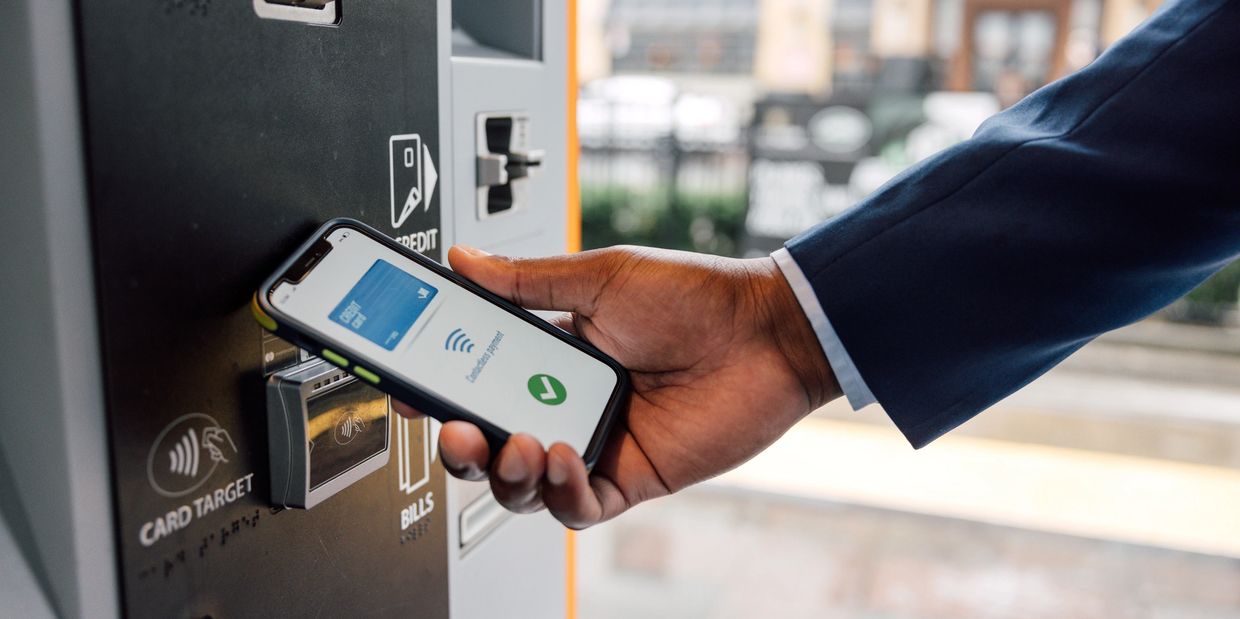 Person making a contactless payment using a smartphone at a payment terminal.