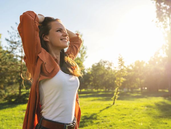 Smiling woman enjoying a sunny day in a green park.