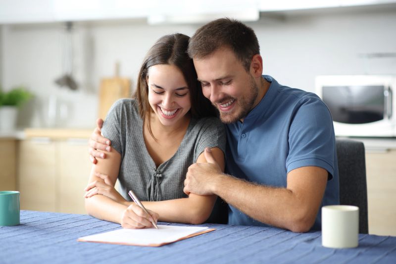 Happy couple signing document at home