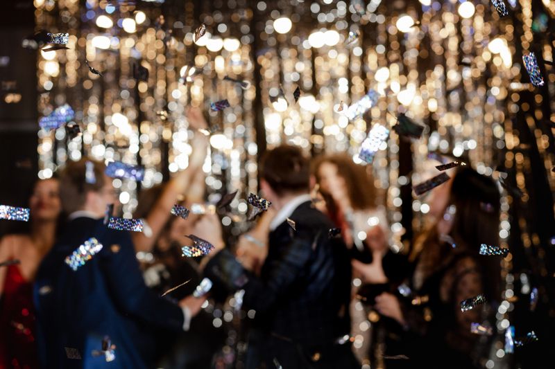 A young happy group of people at a holiday party, confetti falling on them everywhere. Birthday or New Year celebration concept
