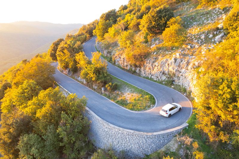 Drone view of a car driving on hairpin bend in the golden hour