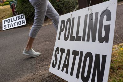 Signs indicating a polling station with a person walking nearby.