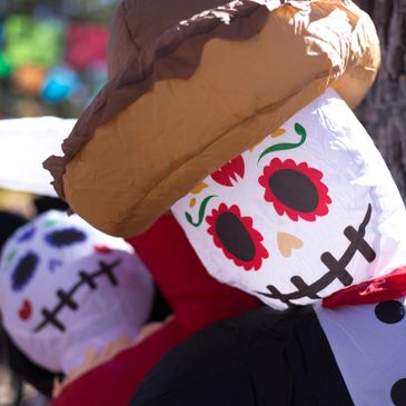 Colorful Day of the Dead skeleton decorations with hats and painted faces.