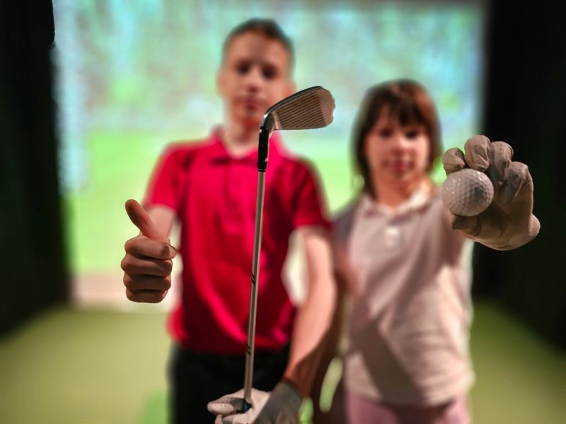 Boy and girl children play golf on a simulator. Teenagers and golf