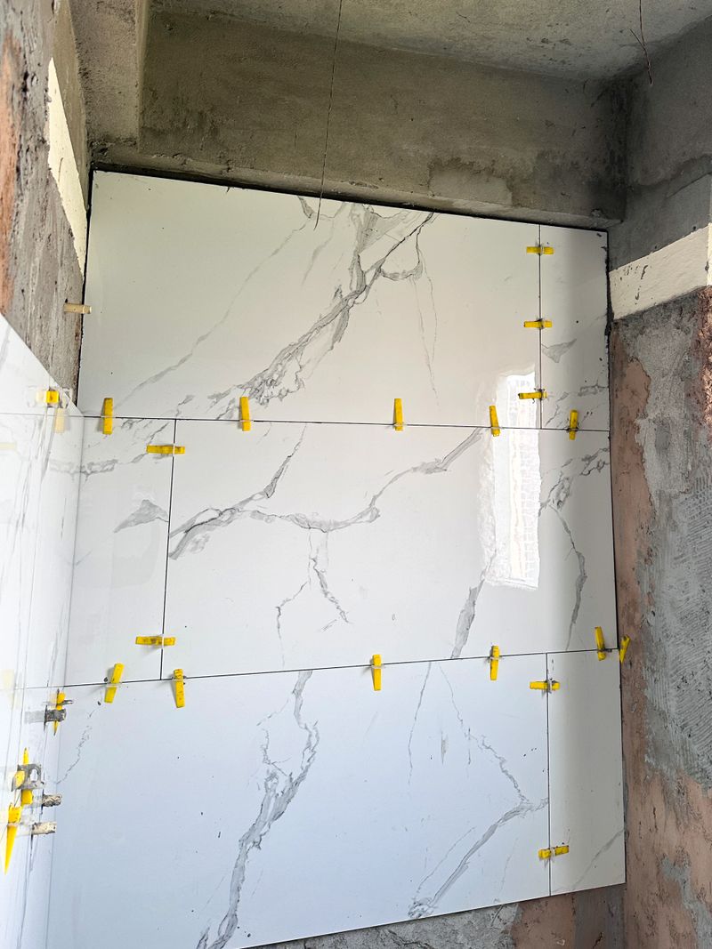 Stock photo of modern bathroom renovation is underway, featuring large, luxurious white and grey marble tiles arranged in a sleek rectangular brick pattern. This under-construction washroom embodies quality craftsmanship and elegant design, perfect for high-end home improvements