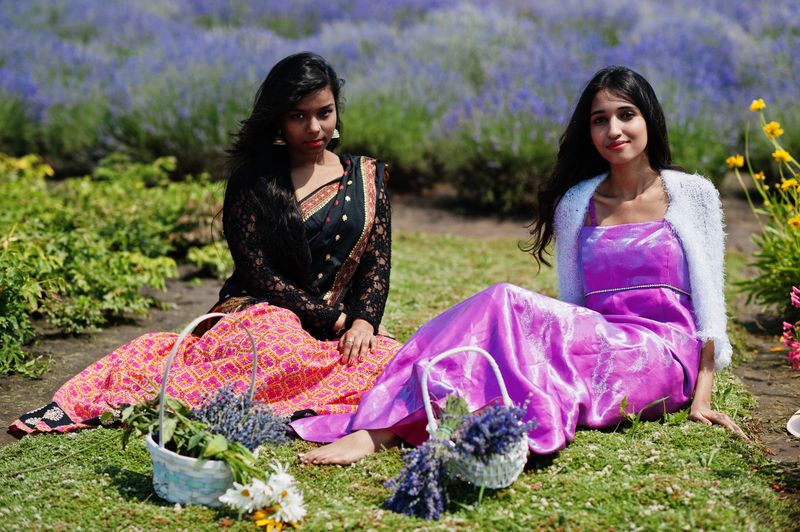Two beautiful indian girsl wear saree india traditional dress in purple lavender field.
