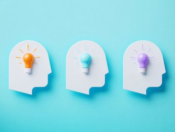 Three heads with colored light bulbs symbolizing ideas and creativity.