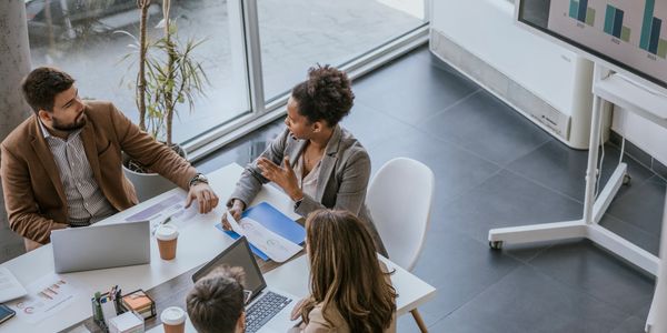 Four professionals discussing business data around a table in an office.