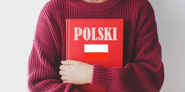 Person holding a red book with "POLSKI" and the Polish flag on it.