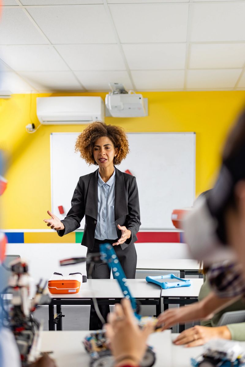 A young teacher instructs her students in a robotics class, fostering creativity and STEM skills.