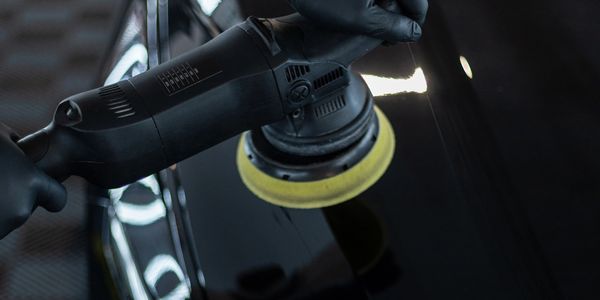 Person using a polishing machine on a black surface.