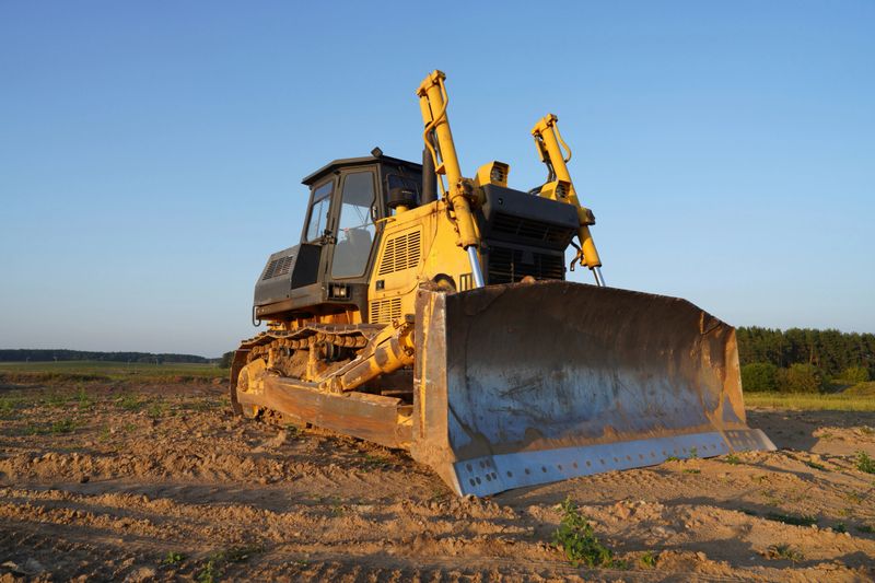 Dozer at construction site, utility trenching. Earth-moving machinery. Bulldozer at road construction. Earth-moving equipment at road work, land clearing, grading, pool excavation, utility trenching.