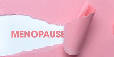 The word 'MENOPAUSE' revealed by torn pink paper.