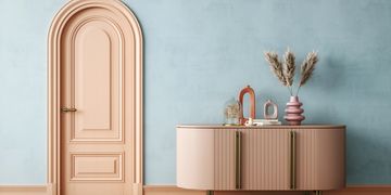 Elegant pastel interior with a curved door and stylish sideboard.