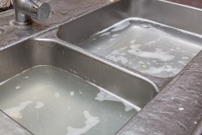 Two kitchen sink basins filled with soapy water ready for washing dishes. Clog cleared in Gulf Breez