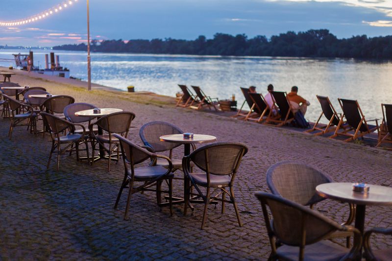 Relaxing evening by the waterfront with chairs, tables, and glowing lights near the calm water