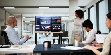 A woman presents data analytics to colleagues in a modern office meeting.