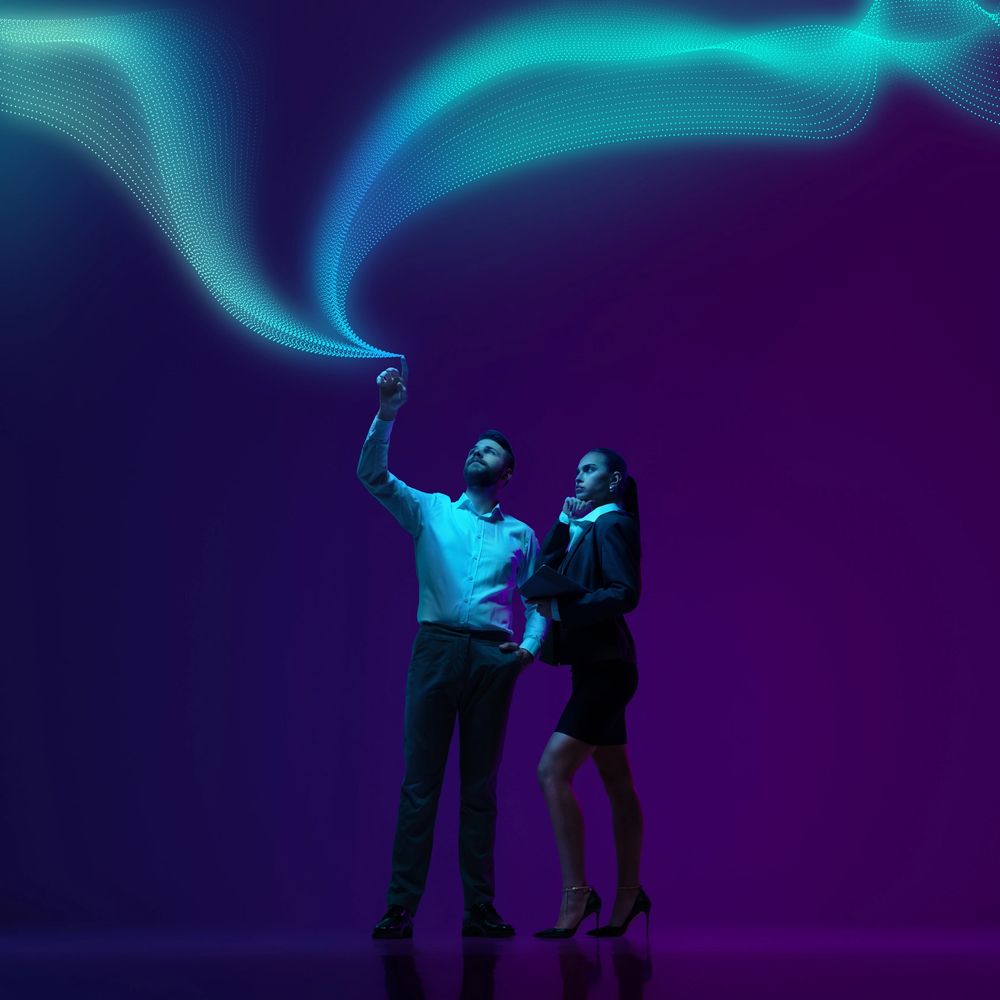 Two professionals interacting with futuristic digital data streams in a dark space.