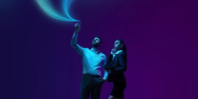 Two professionals interacting with futuristic digital data streams in a dark space.