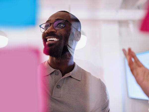 Smiling man wearing glasses in a bright office setting.