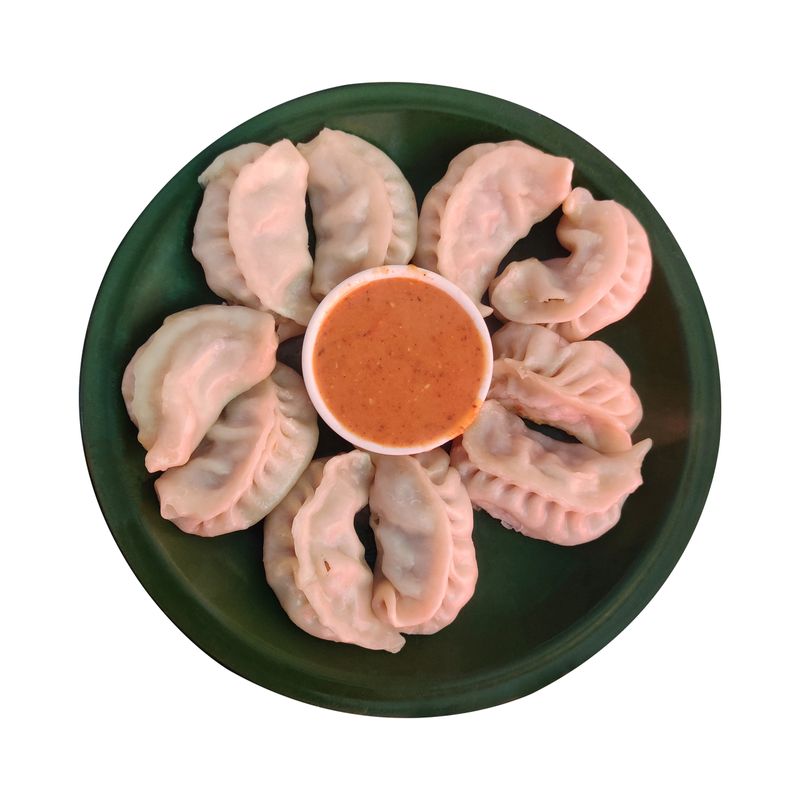 A plate of delicious steamed chicken momos served with spicy dipping sauce, a popular and flavorful dumpling dish from Nepal.