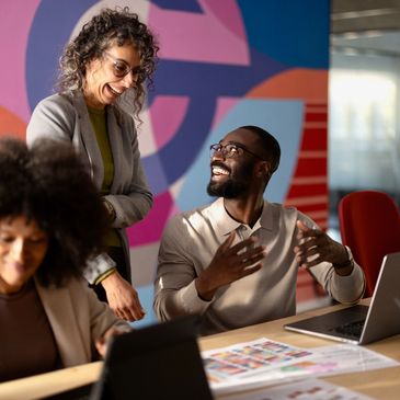 Colleagues smiling and discussing work in a colorful office space.