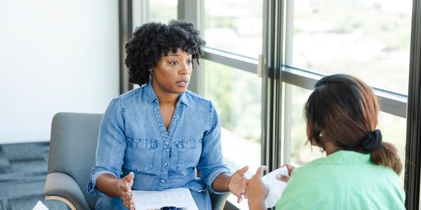 Two women engaged in a serious conversation in an office setting.