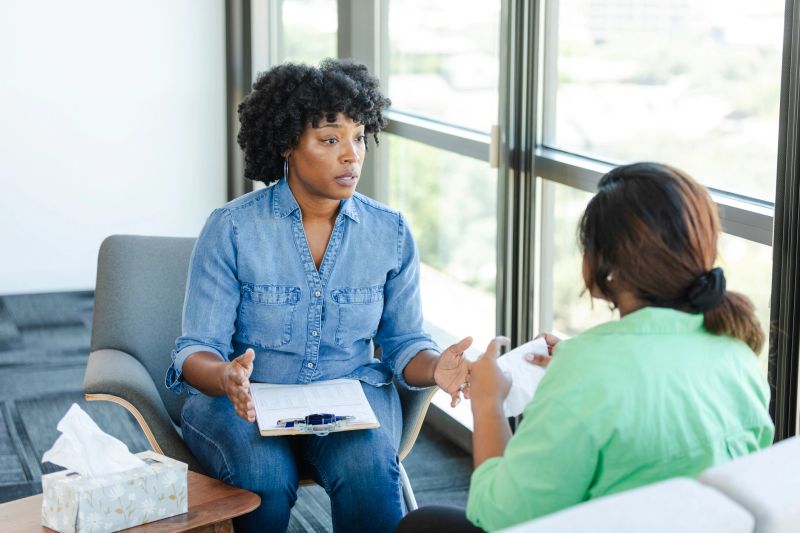 As a young woman cries during a counseling session, a female counselor offers consolation and advice.