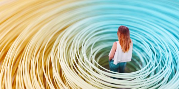 Woman standing inside a spiral of colorful rings blending from yellow to blue.