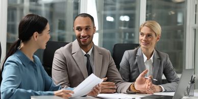 Three professionals engaged in a lively business discussion around a laptop.