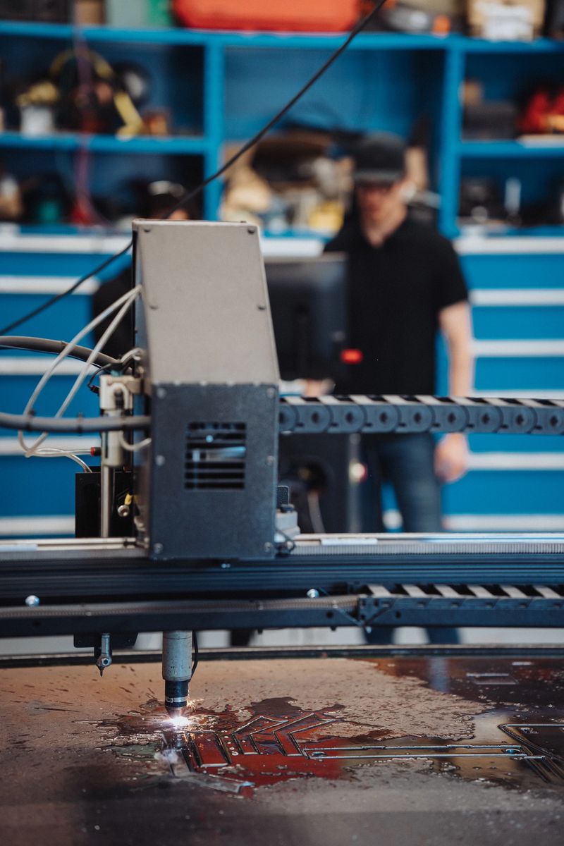 Selective focus on a CNC laser machine creating sparks when engraving metal in a manufacturing and fabrication facility.