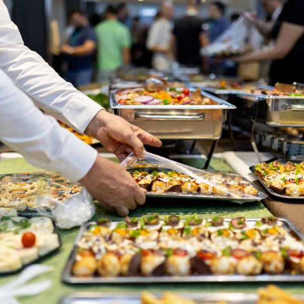Person arranging trays of assorted finger foods at a buffet.