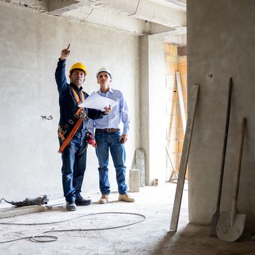 Two construction workers inspecting a building site with blueprints.