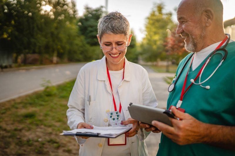 Two healthcare professionals review and analysis the effects of the drug on tablet and clipboard